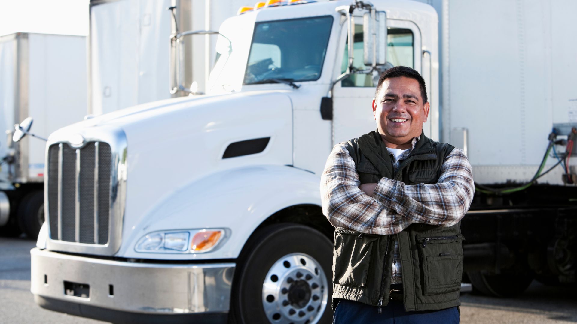 Smiling truck driver standing next to white semi-truck in parking lot