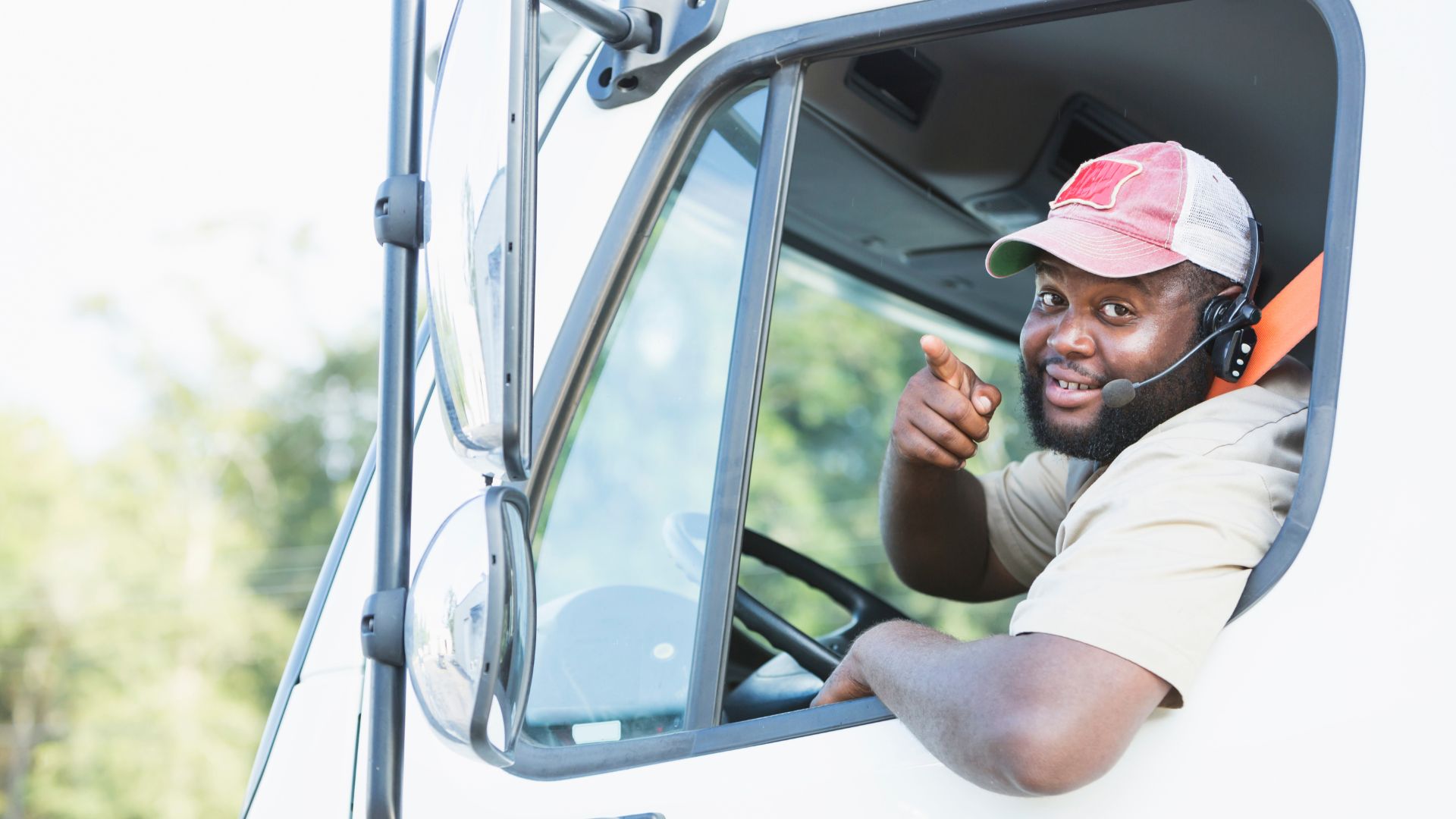 Smiling truck driver gives thumbs up from vehicle window
