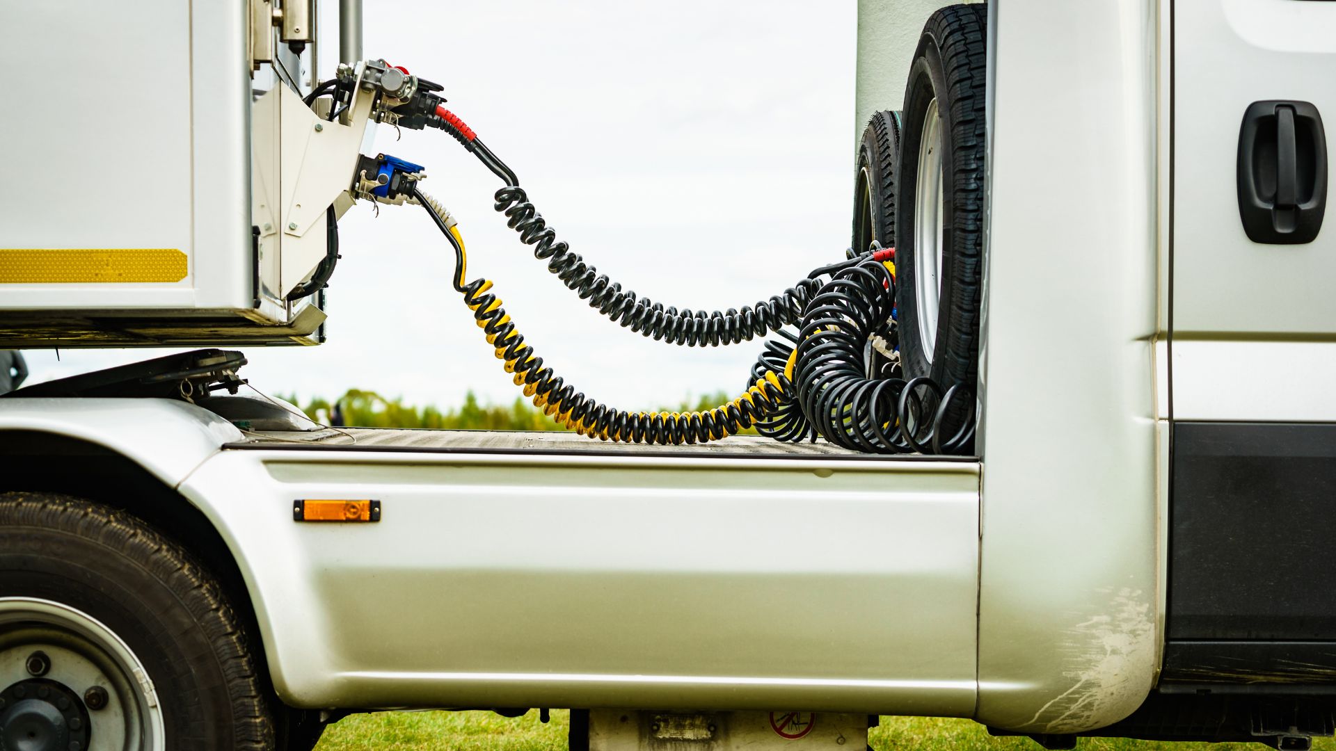 Coiled pneumatic hoses connecting machinery on a white commercial vehicle