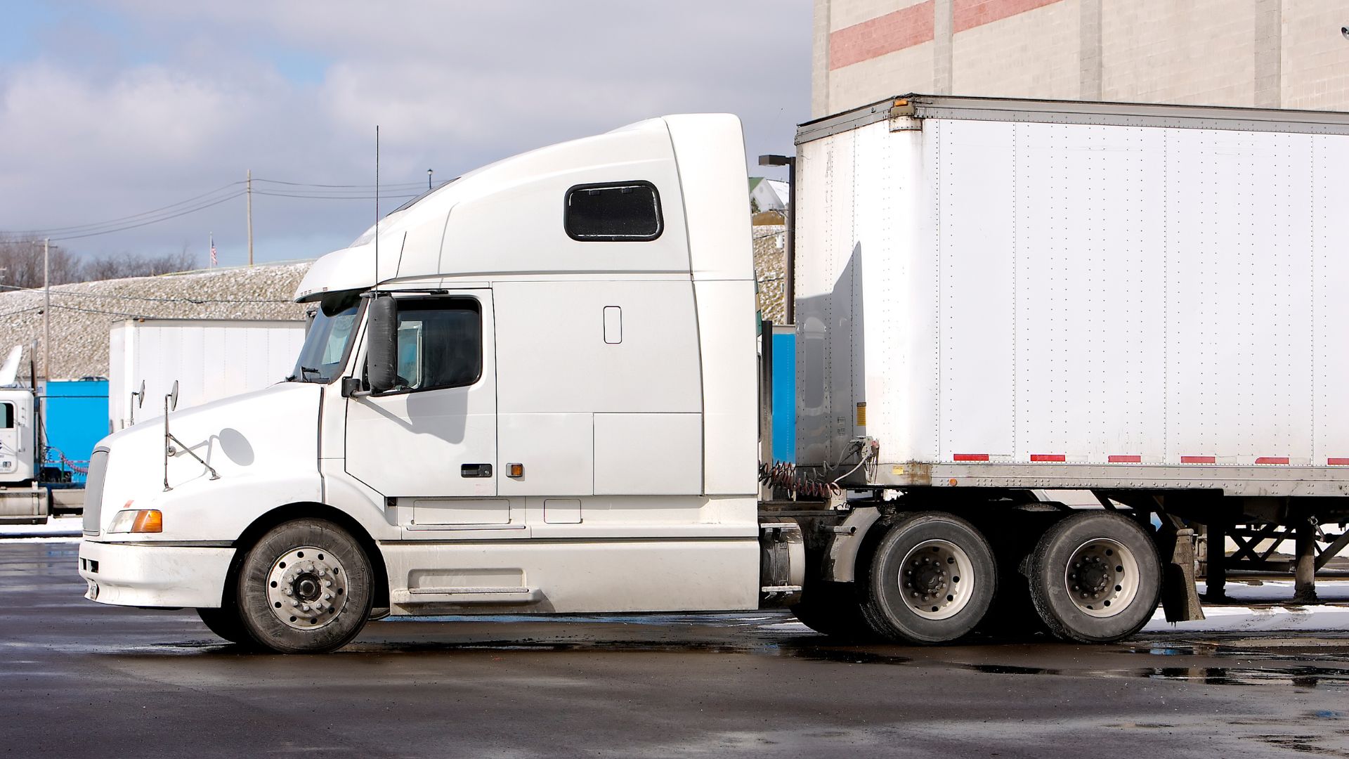 White semi-truck and trailer parked in industrial parking lot