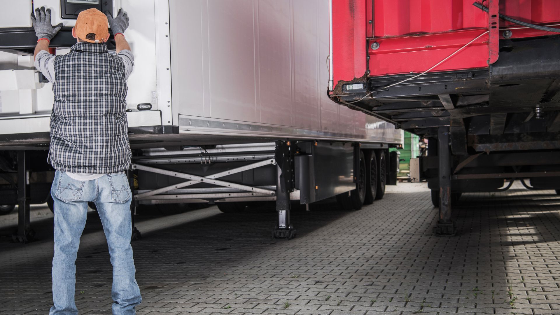 Worker in cap checking truck trailer at loading dock
